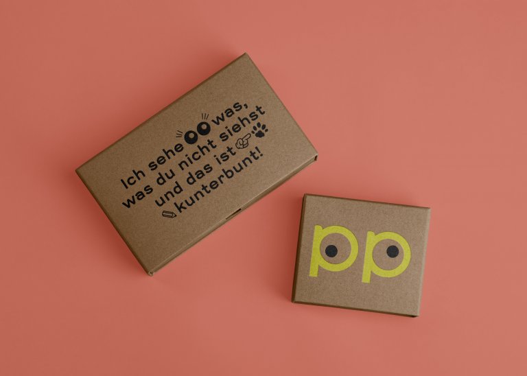 Zwei Boxen aus Karton, eine mit dem Text „Ich sehe was was du nicht siehst“, die andere mit zwei Mal dem Buchstaben p mit jeweils einem versetzten Punkt in der Punze, wirkt wie ein schielendes Augenpaar